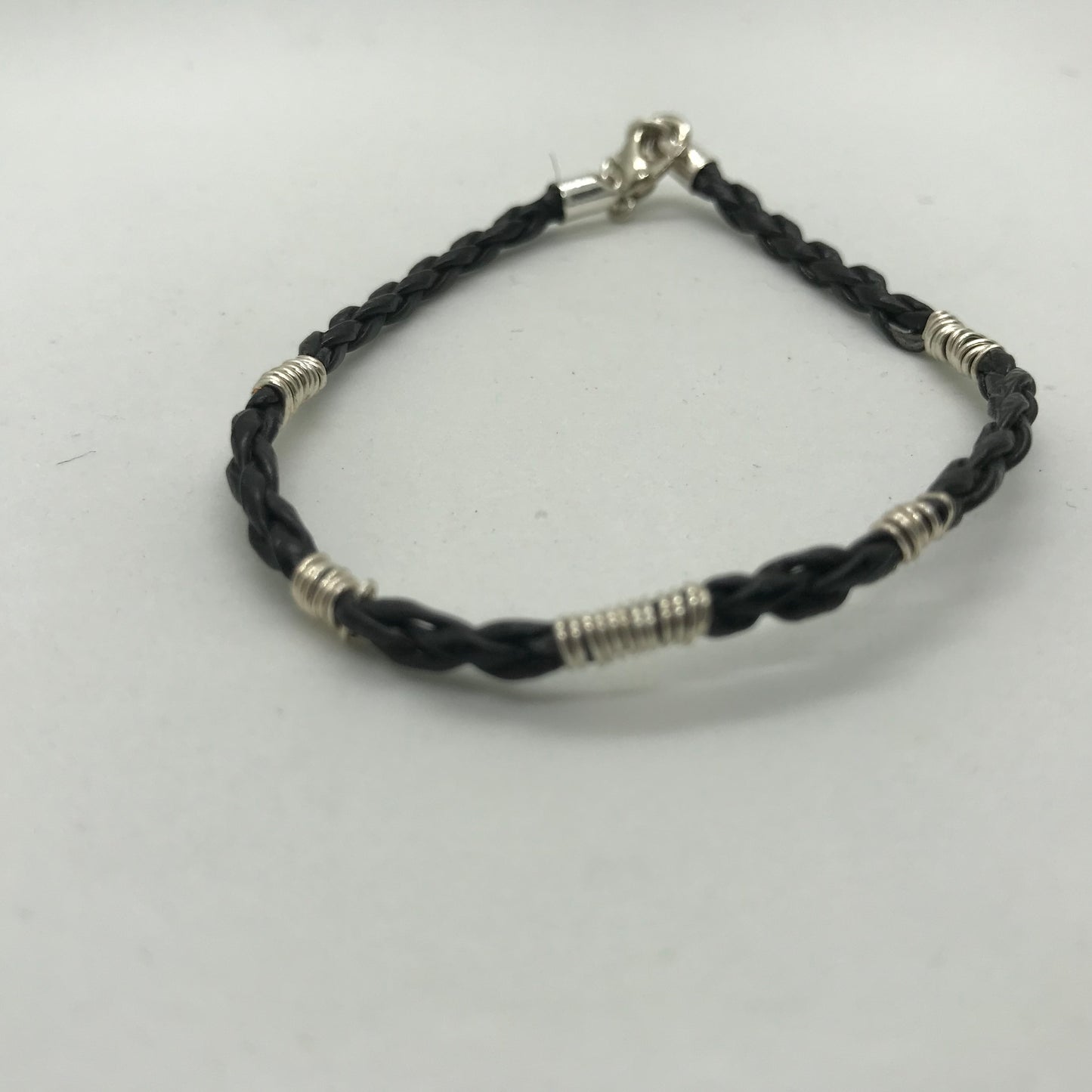 Sort armbånd i flettet skind med sølvviklinger