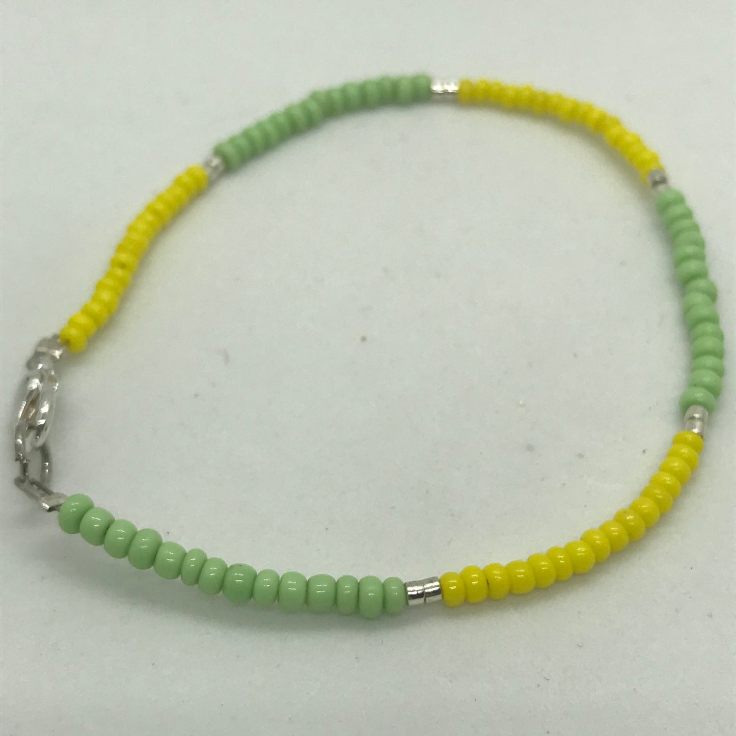 Armbånd på wire med grønne og gule seedbeads