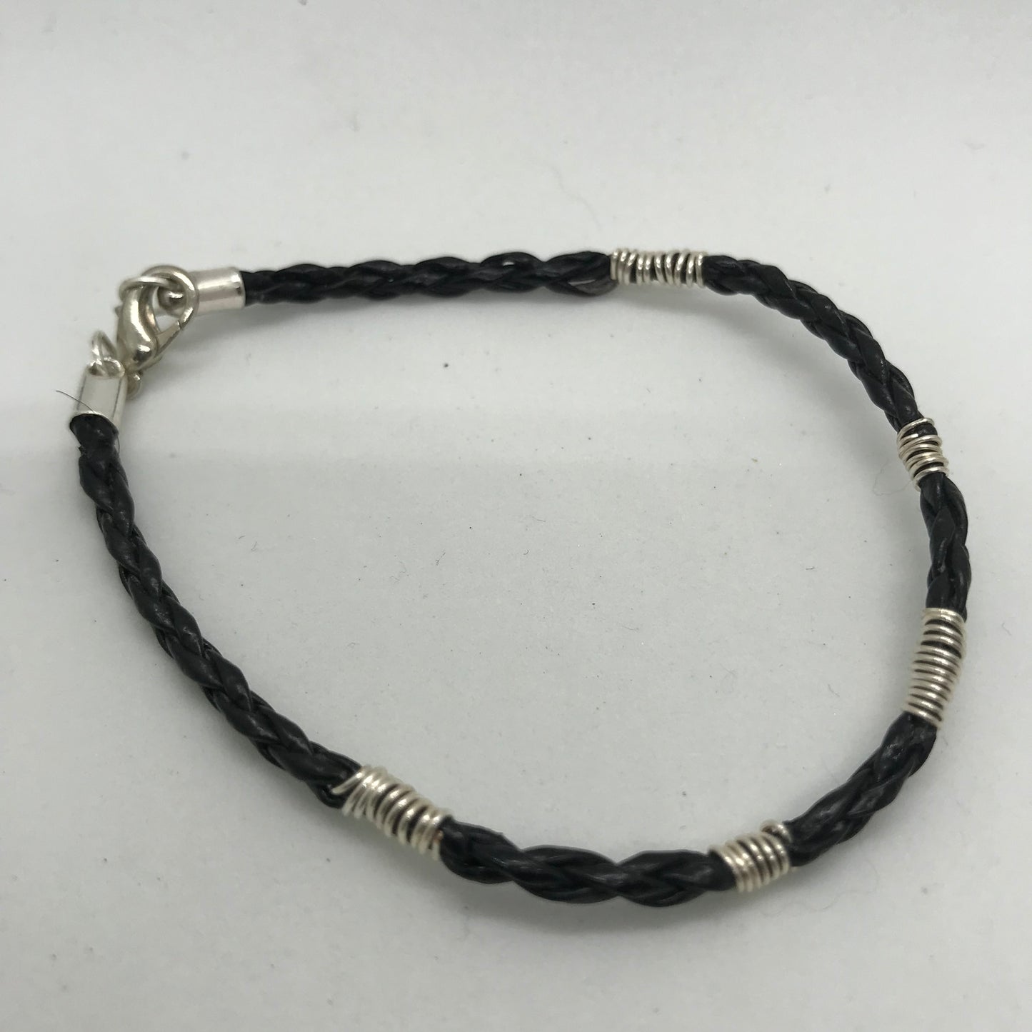 Sort armbånd i flettet skind med sølvviklinger