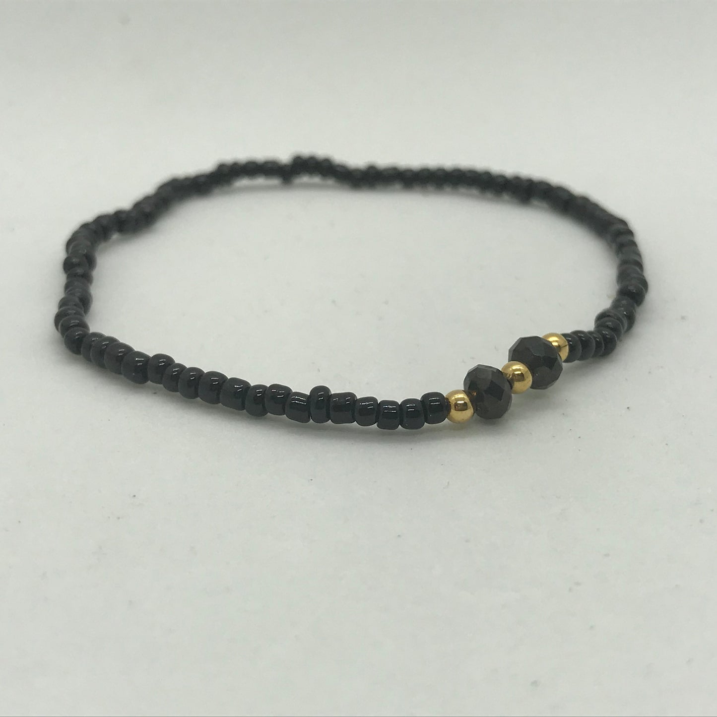 Elastisk armbånd med sorte seedbeads med guld perler