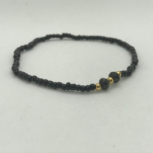 Elastisk armbånd med sorte seedbeads med guld perler