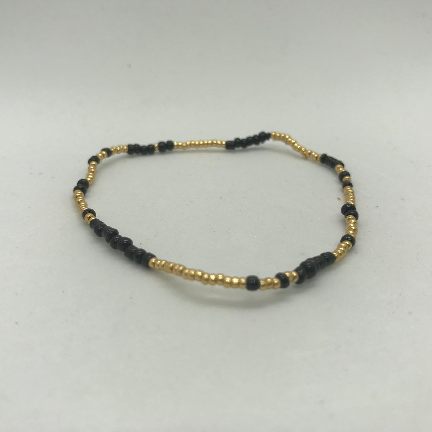 Elastisk armbånd med store sorte seedbeads med guld perler