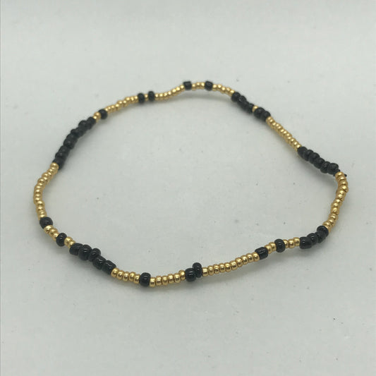 Elastisk armbånd med store sorte seedbeads med guld perler