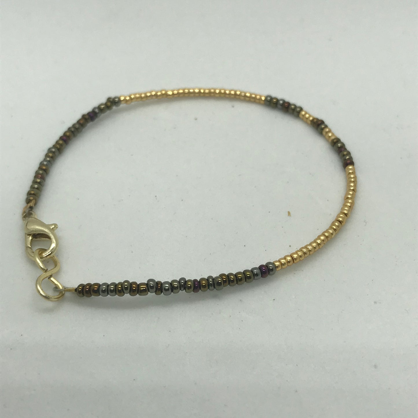 Armbånd på wire med guld og brune seedbeads