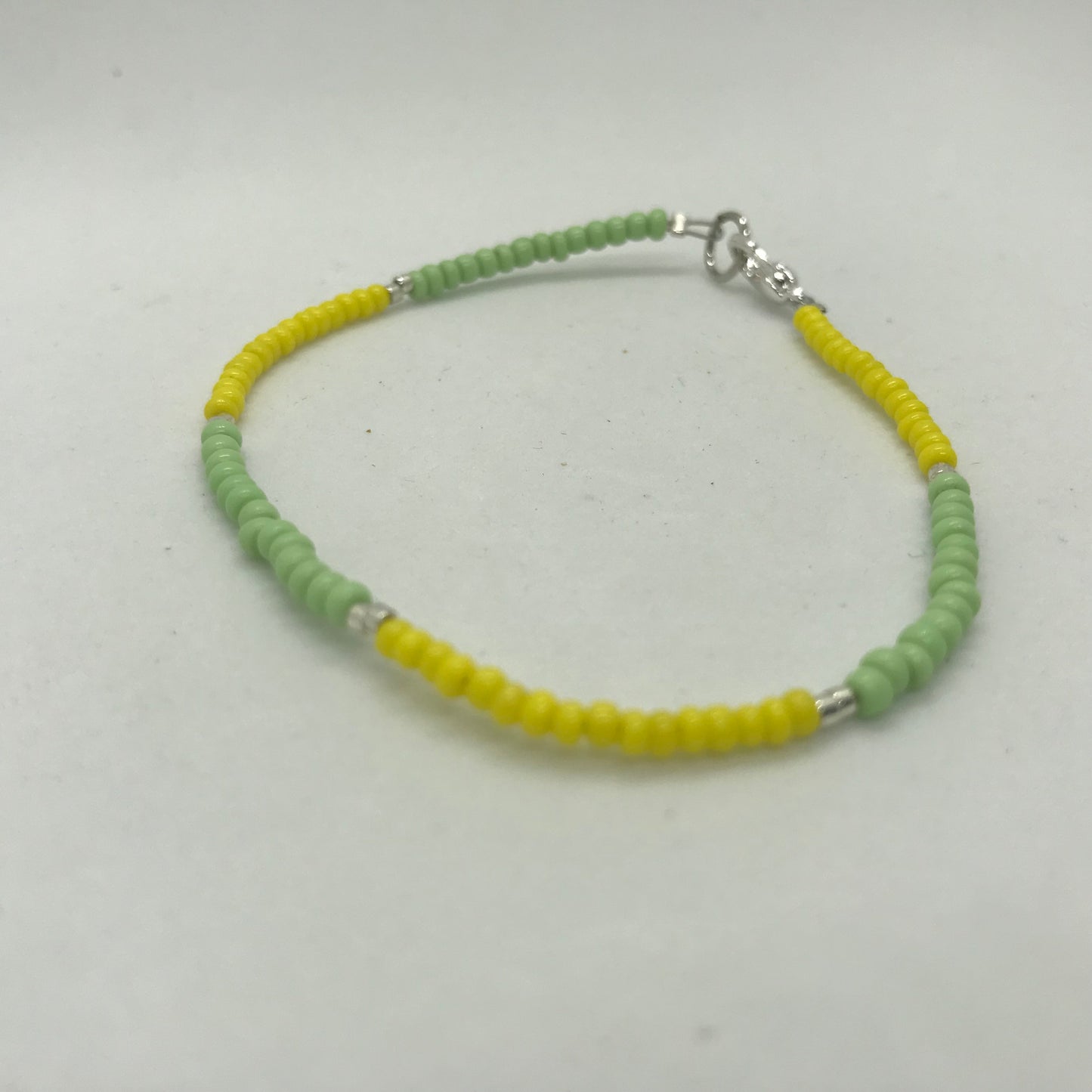 Armbånd på wire med grønne og gule seedbeads